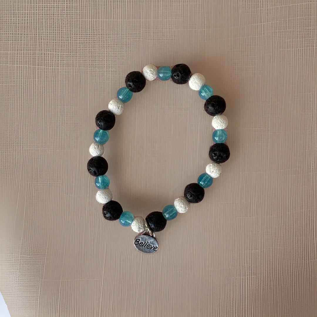Beaded bracelet with black, blue, and white beads on a beige surface