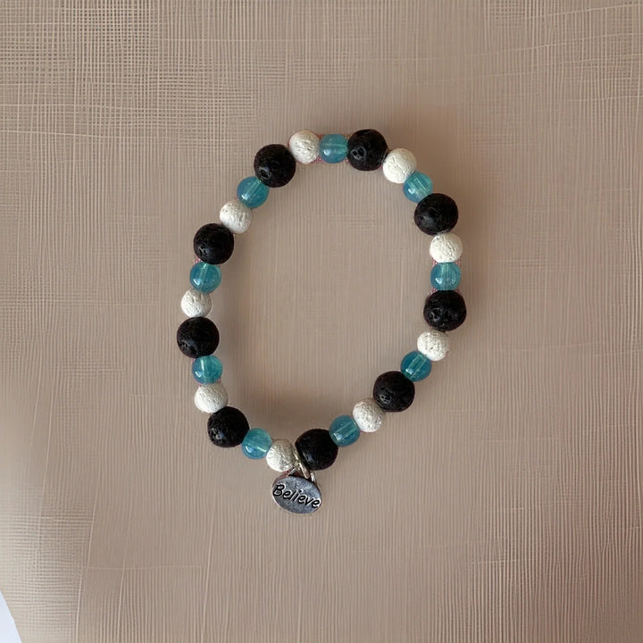 Beaded bracelet with black, blue, and white beads on a beige surface