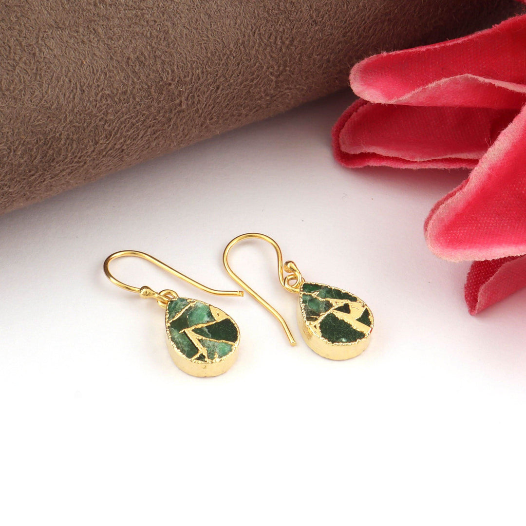 Gold earrings with green gemstones on a white background