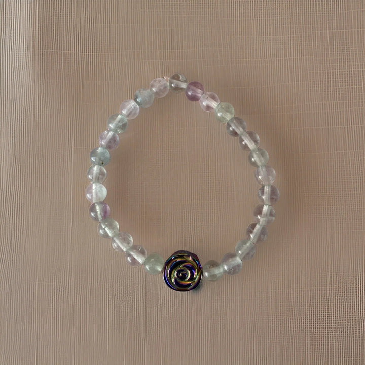 Beaded bracelet with a rose-shaped charm on a beige background