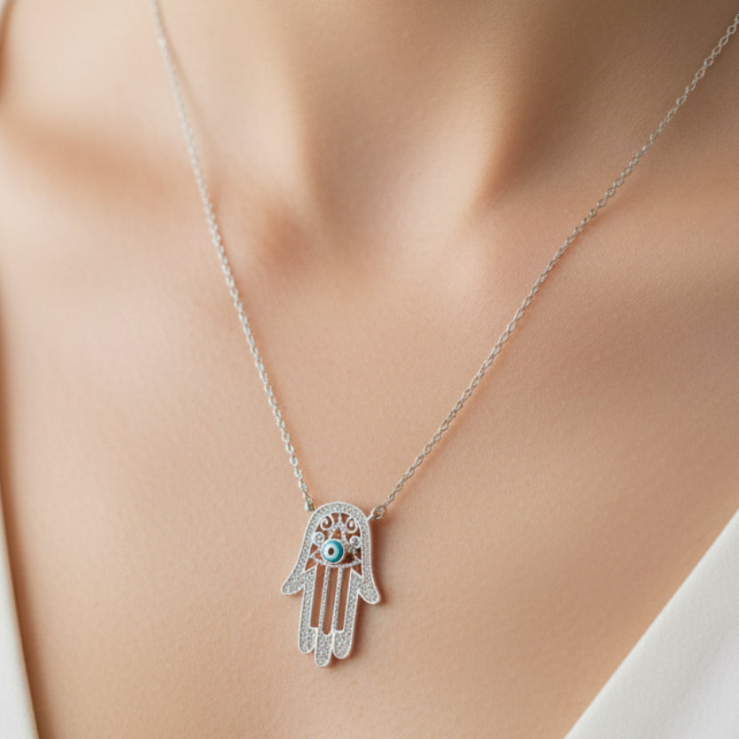 Silver necklace with a Hamsa hand pendant on a wooden surface