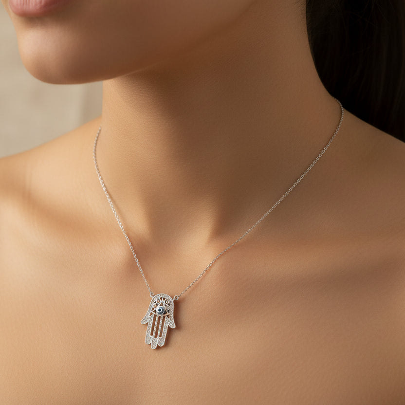 Silver hand-shaped pendant necklace with a blue gemstone on a wooden surface