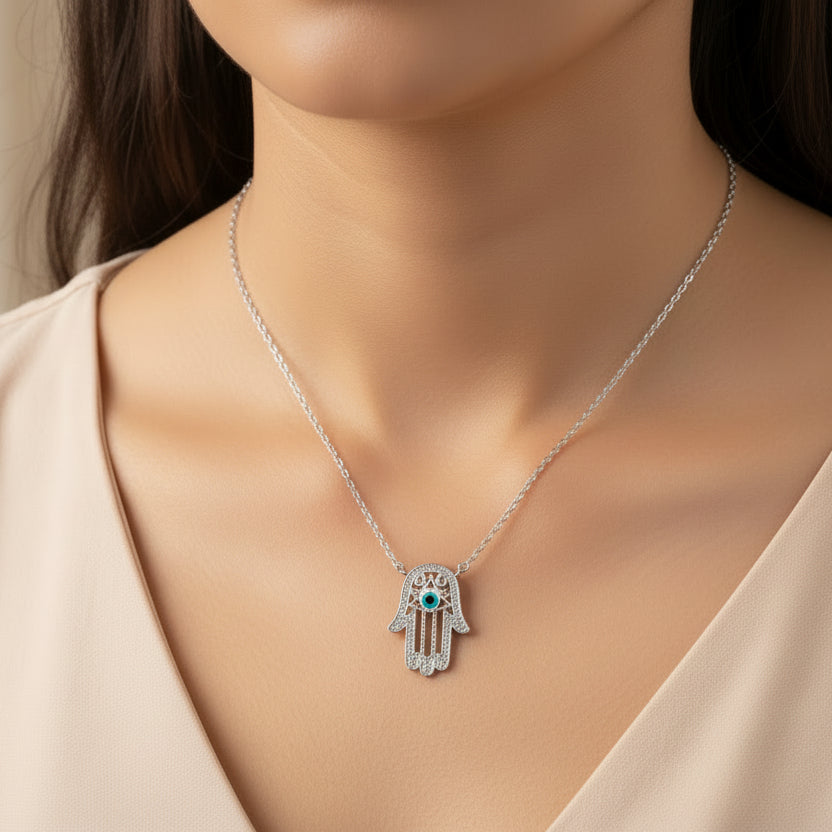 Silver Hamsa hand necklace with blue gemstone on a dark background