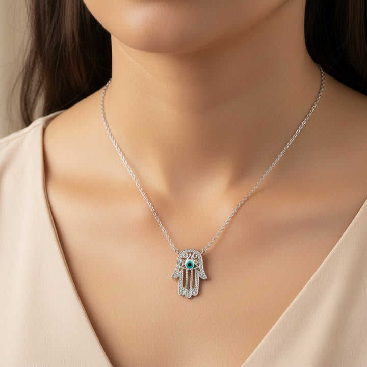 Silver Hamsa hand necklace with blue gemstone on a dark background