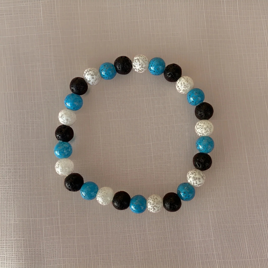 Beaded bracelet with blue, black, and white beads on a textured surface