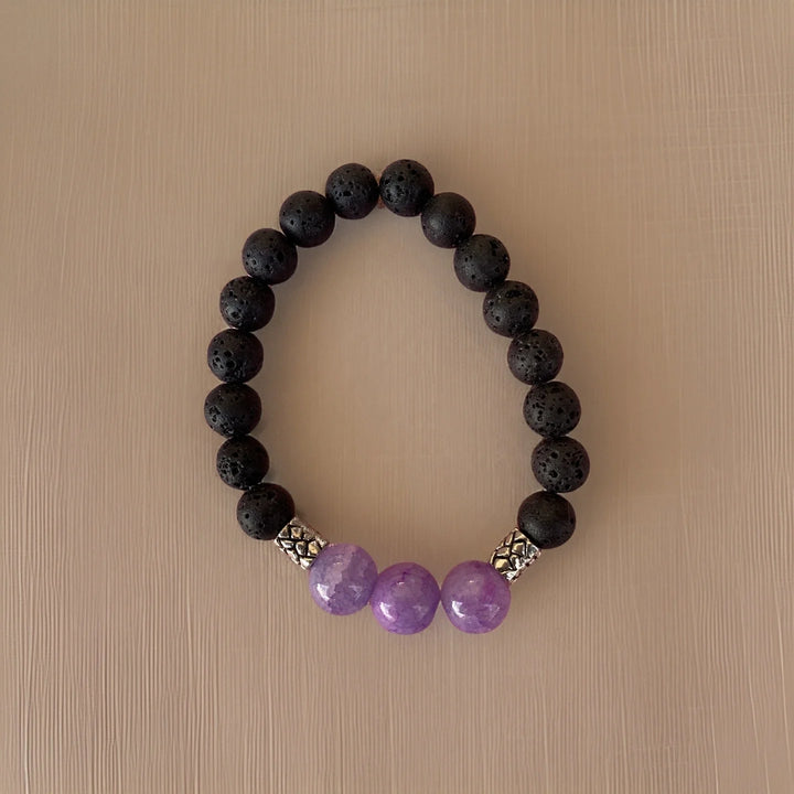 Black beaded bracelet with purple beads on a beige background