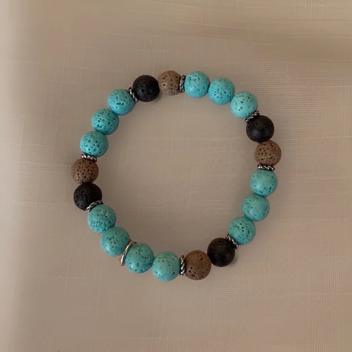 Beaded bracelet with turquoise, black, and brown beads on a beige background